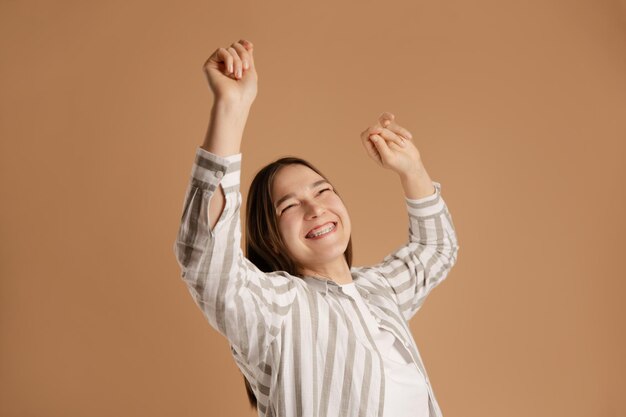 Photo young woman dancing on beige background enjoy health with brace system