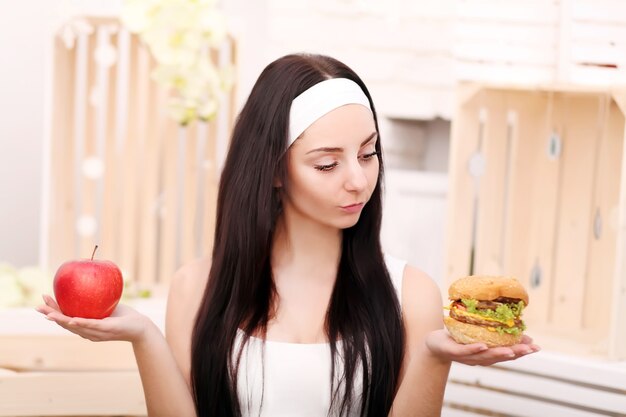 A young woman decides between hamburger and apple