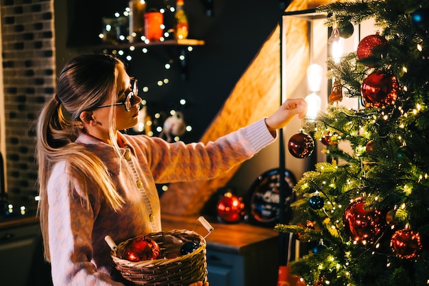 写真 若い女性はおもちゃでクリスマスツリーを飾ります。休日の準備