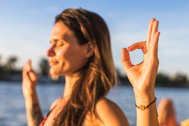 Foto giovane donna in profonda concentrazione e mediazione sulla riva di un fiume