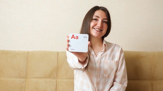 Молодая женщина демонстрирует открытки с буквами английского алфавита и произносит звуки и слова