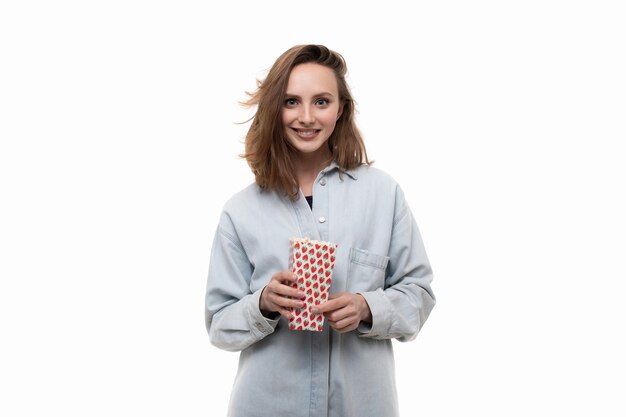 A young woman in a denim shirt eats popcorn