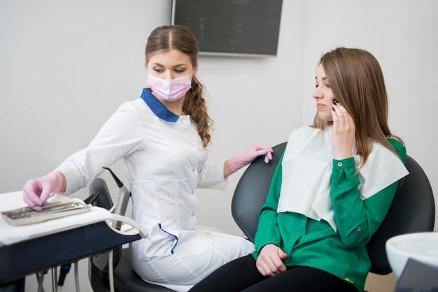 Молодая женщина у стоматолога жалуется на зубную боль. Женский доктор, собирание стоматологический инструмент. лечение зубов