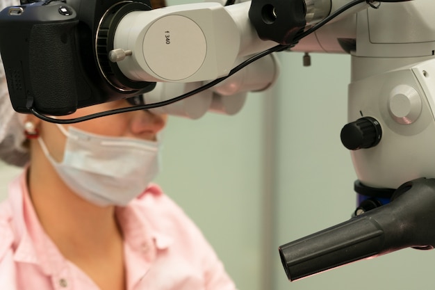 Foto il medico dentista della giovane donna osserva tramite un microscopio professionale in una clinica dentale.