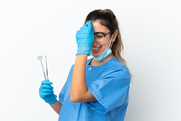 Young woman dentist holding tools isolated on white background laughing