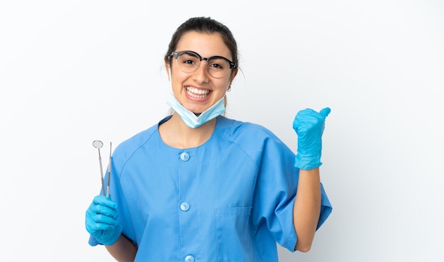 Strumenti di tenuta del dentista della giovane donna isolati su fondo bianco che indica il lato per presentare un prodotto