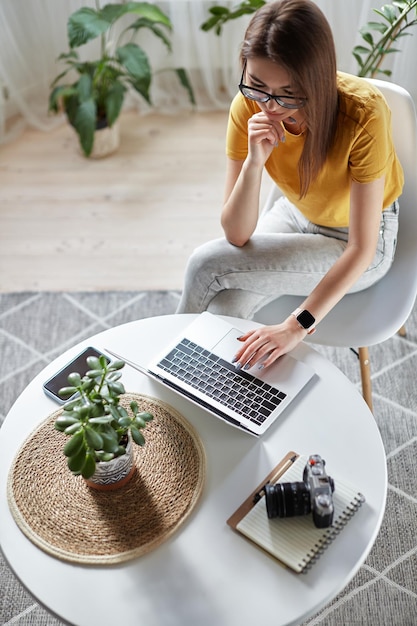 Young woman designer or freelancer working at home using computer sitting at table at home