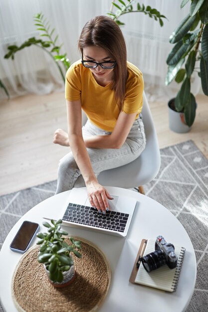 Foto designer di giovane donna o libero professionista che lavora a casa utilizzando il computer seduto al tavolo a casa