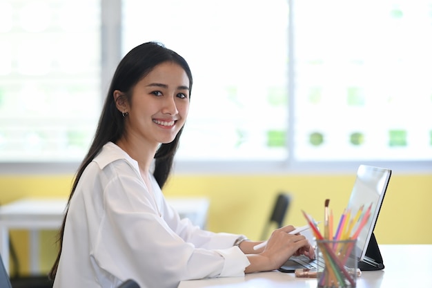 Young woman designer working with computer tablet and smiling to camera.