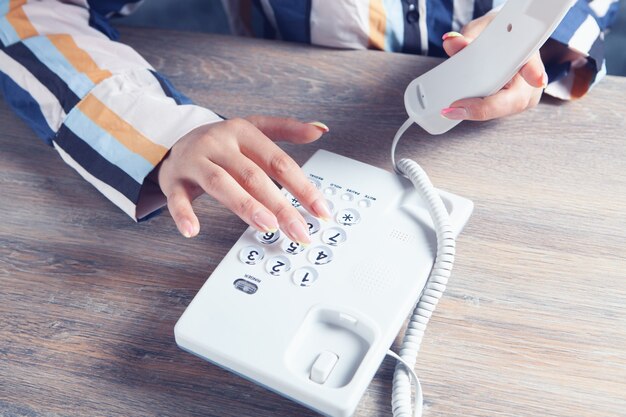 Young woman dialing by home phone