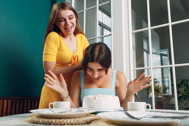 Young woman dips face in white cake with cream. Happy birthday concept.