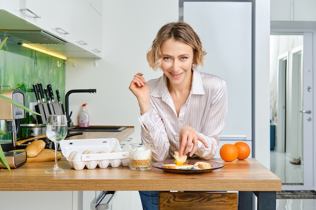 Young woman  dips toast in fried egg