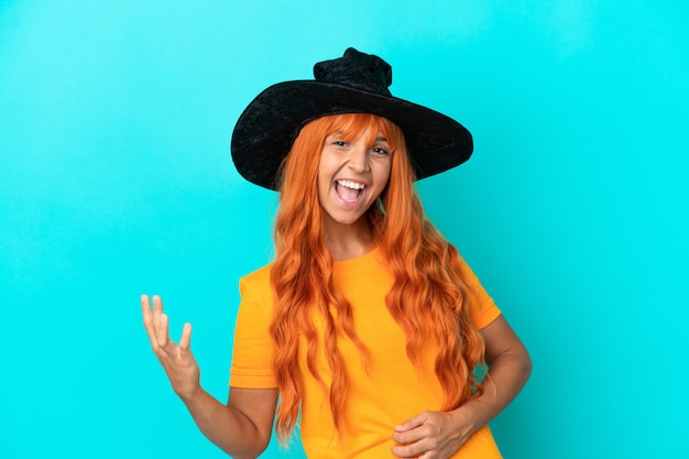 Young woman disguised as witch isolated on blue background making guitar gesture