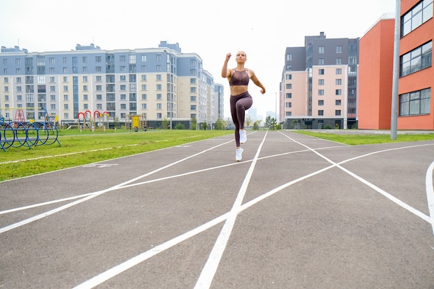 若い女性は、屋外のスタジアムでスポーツ用品を使ってスポーツトレーニングを行っています。ボディービルと健康のためのライフスタイルとトレーニングエクササイズ。