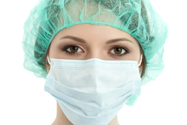 Young woman doctor in cap and face mask close-up portrait isolated. Healthcare, medical and surgery concept