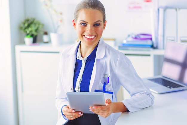 Young woman doctor holding a red heart standing on hospital background