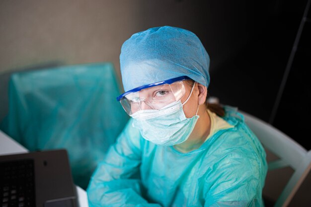 Young woman doctor intern in mask and uniform at workplace