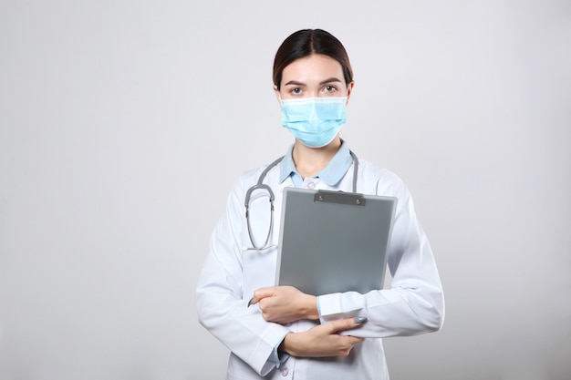 Young woman doctor on light background closeup