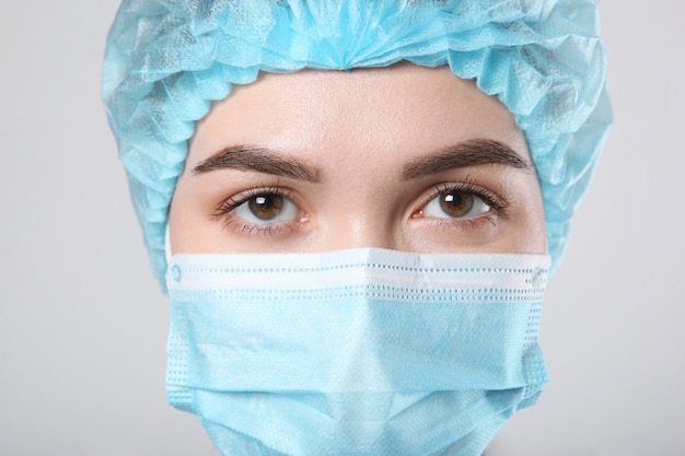 Young woman doctor on light background closeup