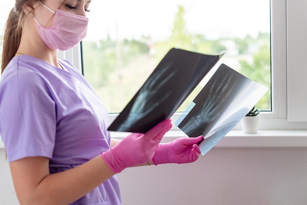写真 診療所でx線放射線画像を見ている若い女性医師 患者の骨のスキャンをレビューする医師外科医 スクリーニングテストの結果 医療検査 医療放射線学の概念