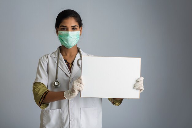 빈 보드, 코로나 바이러스, Covid-19의 전염병의 개념을 들고 의료 마스크에 젊은 여자 의사.