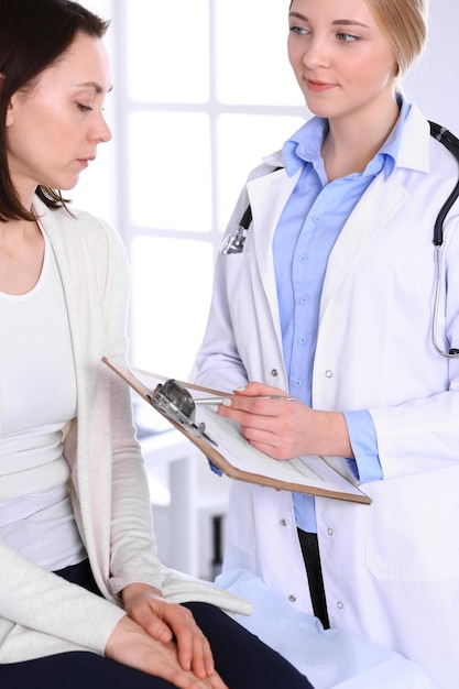 Young woman doctor and patient at medical examination at hospital office. Blue color blouse of therapist looks good. Medicine and healthcare concept.