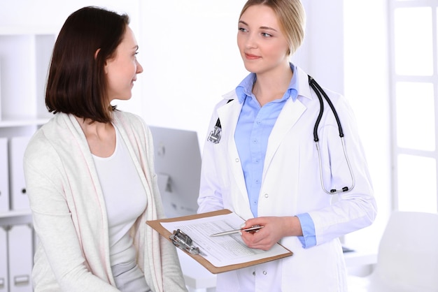 Giovane donna medico e paziente alla visita medica presso l'ufficio dell'ospedale. la camicetta blu del terapeuta sembra buona. concetto di medicina e assistenza sanitaria.