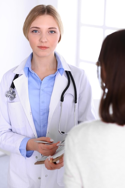 Foto giovane donna medico e paziente alla visita medica presso l'ufficio dell'ospedale. la camicetta blu del terapeuta sembra buona. concetto di medicina e assistenza sanitaria.