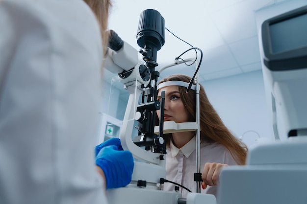 A young woman at a doctor's appointment An optometrist examines the patient's vision using a slit lamp