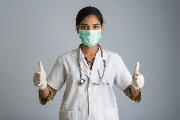 Young woman doctor wearing medical face mask Showing thumbs up. Doctor woman wearing surgical mask for corona virus.