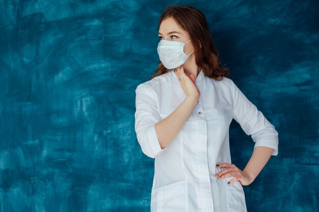 Young woman doctor in a white coat and medical mask. The medicine