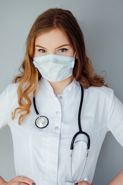 young woman doctor in a white coat and medical mask. the medicine