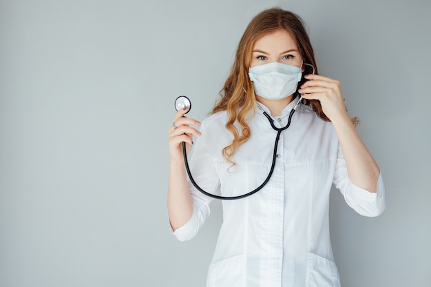 Young woman doctor in a white coat and medical mask. The medicine