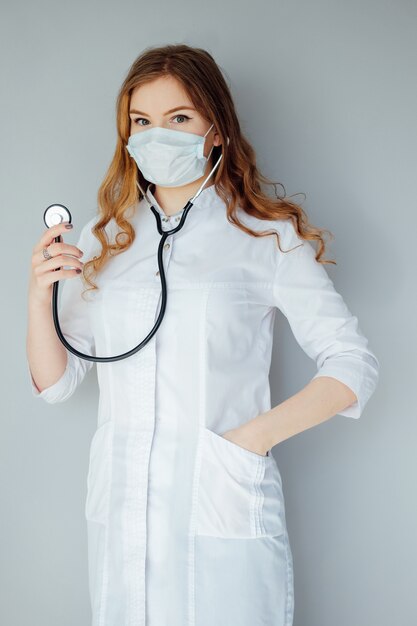 Young woman doctor in a white coat and medical mask. The medicine