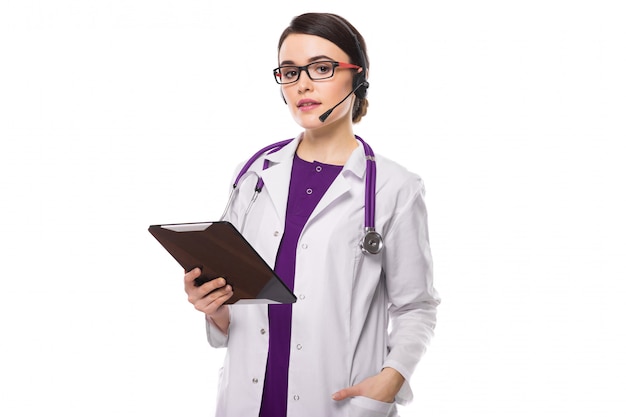 Photo young woman doctor with stethoscope and headphones holding tablet in her hands in white uniform