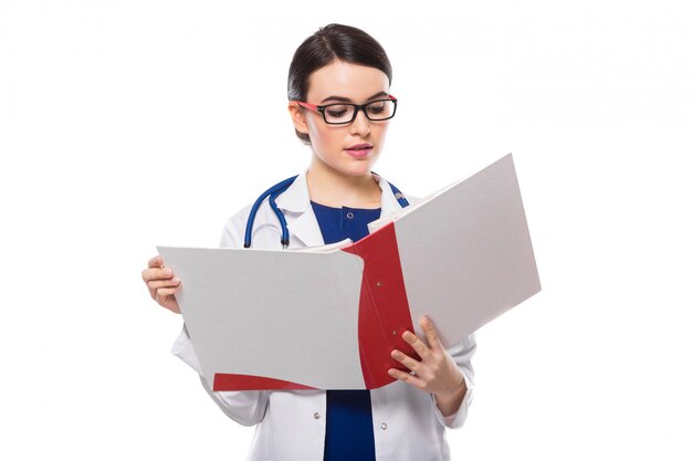 Young woman doctor with stethoscope holding binder in her hands in white uniform on white 