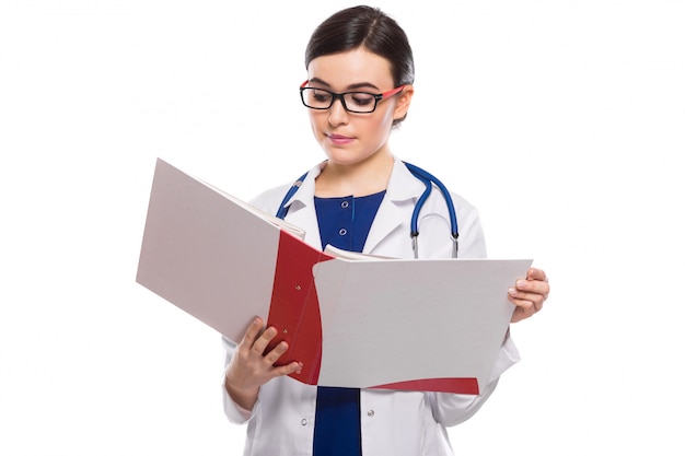 Young woman doctor with stethoscope holding binder in her hands in white uniform on white 