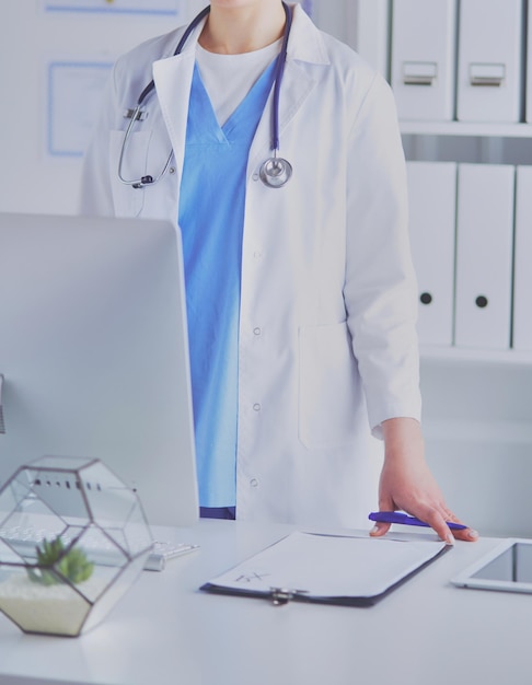 Young woman doctor at work while pointing at computer in\
hospital office