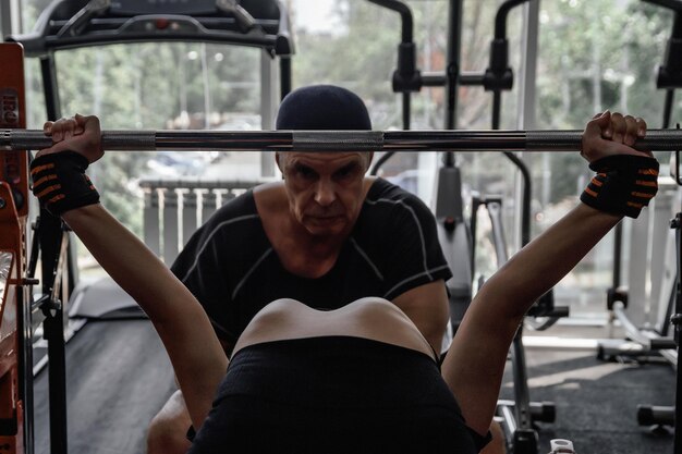 Photo young woman does barbell press under the supervision of trainer