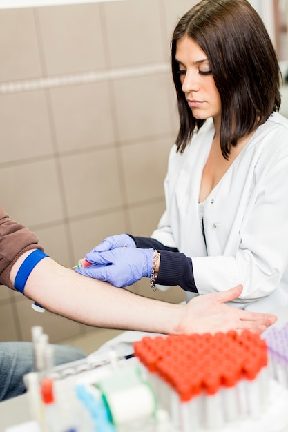 Giovane donna facendo prelievo di sangue nel moderno laboratorio medico