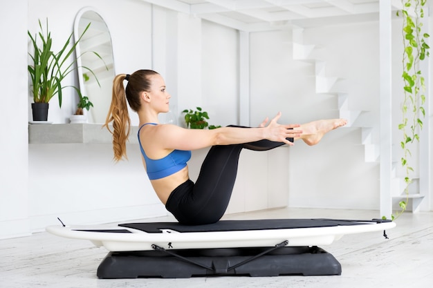 Young woman doing a boat pose on a surfset to strengthen her hips and flexors