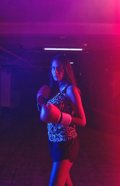 Young woman doing boxing training at the gym she is wearing boxing gloves