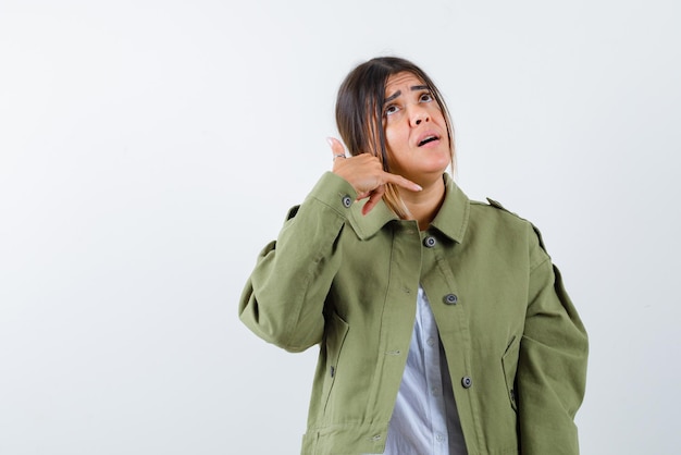 Young woman doing a call me hand gesture on white background