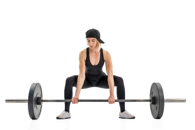 Young woman doing deadlift with a barbell isolated on white wall