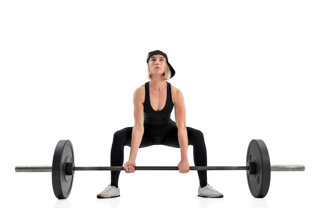 Young woman doing deadlift with a barbell isolated on white wall