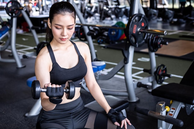 Young woman doing exercise with dumbbell in modern gym.