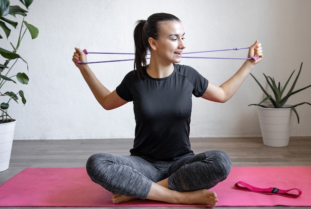 Young woman doing exercises with a fitness elastic band at home