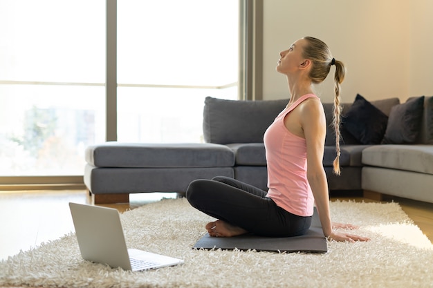 Young woman doing exercises on yoga mat