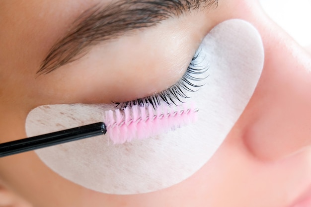 Young woman doing eyelash lamination procedure in a beauty salon, close-up