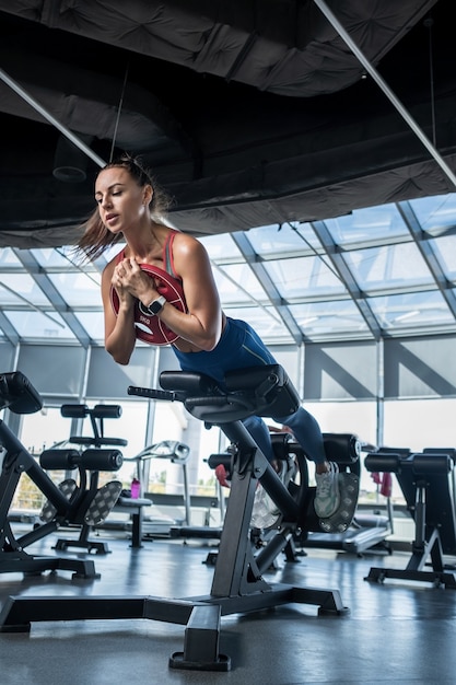 Young woman doing hyperextension with weight plate at gym